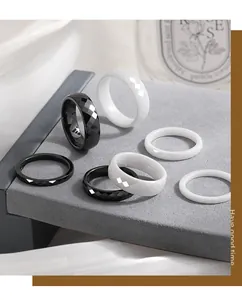 Close-up of faceted and smooth black and white ceramic stackable rings on grey display.