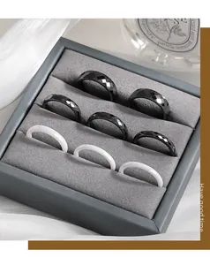 Collection of faceted black and smooth white ceramic rings in a gray display box.