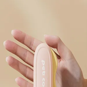 Close-up view of a pink folding pet comb held in hand for grooming and size reference.