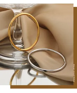 Close-up of minimalist gold and silver titanium steel open bangles on beige silk fabric