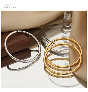 Detailed shot of minimalist gold and silver plated titanium steel open bangles on elegant silk