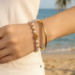 Korean style gold plated open bangle and pearl rose bracelet set worn on wrist at beach
