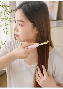 Asian woman using a pink and yellow portable folding travel comb on long hair