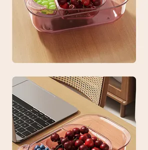 Detailed view of a pink double-layer partitioned fruit drainer box on a wooden desk.