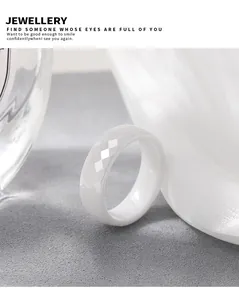Macro view of a faceted white ceramic ring with a minimalist rhombus pattern design.