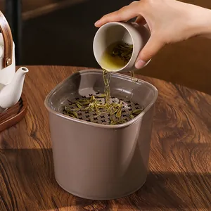 Detail of a brown desktop tea dregs trash can with a removable strainer tray for drainage.
