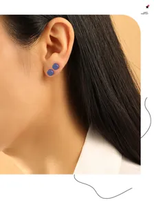 Gedetailleerd overzicht van minimalistische blauwe ronde biokeramische oorknopjes op het oor