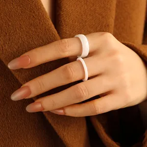 Minimalist white ceramic stackable rings with rhombic facets displayed on a finger