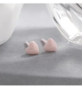 Macrodetail van minimalistische roze hartvormige keramische oorbellen voor gevoelige oren