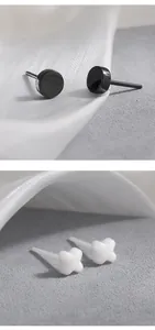 Gedetailleerde macro-weergave van minimalistische zwarte ronde en witte keramische oorknopjes.