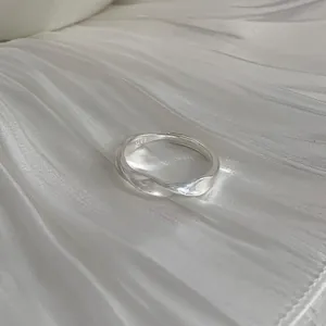 Detail shot of a minimalist 925 sterling silver twisted ring on white fabric.