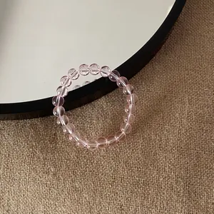 Macro detail of a translucent pink beaded crystal bracelet on a textured background