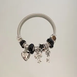 Vue détaillée d'un bracelet ouvert en acier argenté avec breloques cœur, nœud et étoile