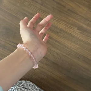 A close-up view of a pink translucent beaded crystal bracelet worn on a female wrist