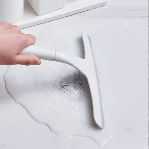 White T-shaped squeegee wiping soapy water and hair off a clean white marble tile surface
