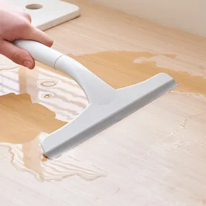 White handheld window squeegee tool effectively removing water from a wooden surface.