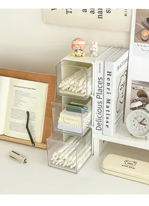 Three-tier clear acrylic drawer organizer on a white desk with stationery