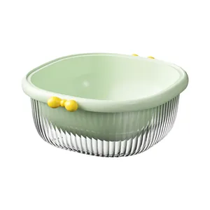 Light green double-layer plastic kitchen drain basket with yellow bow handles on white background.