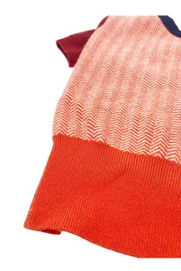 Close-up of dog knit sweater featuring orange herringbone pattern and ribbed hem detail.