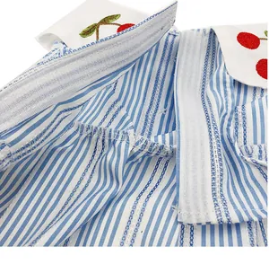 Macro detail of the pet dress showing the Velcro closure and cherry embroidery on stripes.