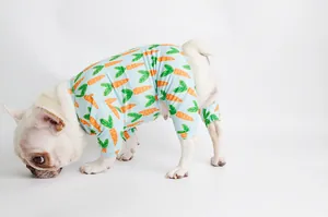 Close-up of light blue dog pajamas with orange carrot print on a white French Bulldog