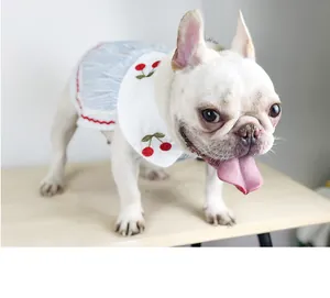 Detailed view of dog wearing a thin summer dress with cherry embroidery and blue stripes