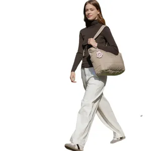 Mujer con bolso acolchado beige y un llavero conmemorativo de pata de perro rosa