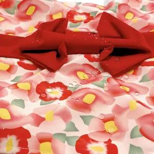 Close-up detail of a floral pet kimono fabric showing waterproof droplets and a red bow.