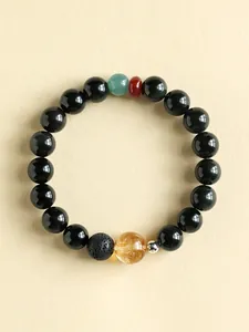 Detail view of obsidian and citrine beaded bracelet on a cream textured background