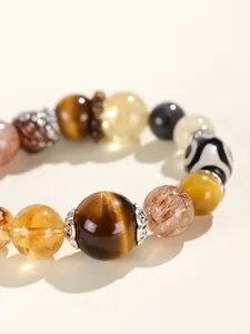 Makro-Detailansicht eines Armbands aus Natur-Tigerauge und Edelsteinen mit Dzi-Perle.
