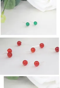 Detaillierte Nahaufnahme bunter runder Kristallohrstecker auf elegantem weißem Stoff.