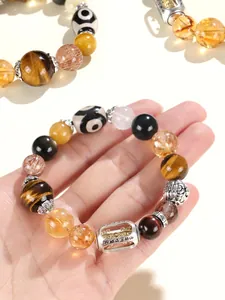Detailaufnahme eines handgefertigten Armbands aus Tigerauge und Dzi-Perlen mit Pi Xiu