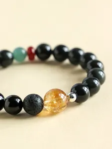 Macro detail of obsidian and yellow citrine bracelet with textured lava stone bead.