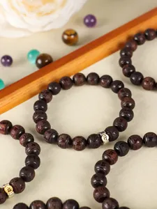 Macro detail of red sandalwood beads with carved zodiac signs and metal accent charm
