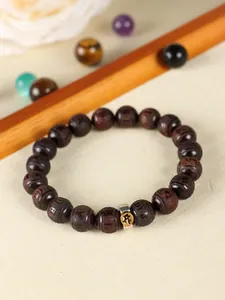 Macro view of red sandalwood beaded bracelet featuring carved metal charm detail.