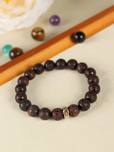 Close-up detail of a dark sandalwood beaded bracelet with an engraved metallic bead.