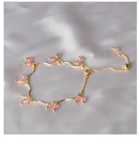 Dettaglio del bracciale a catena ondulata dorata con perle di quarzo fragola.