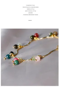 Primo piano di un braccialetto a catena dorata con perle di pietre preziose colorate.