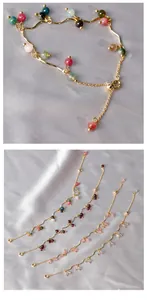 Dettaglio di bracciali a catena d'oro ondulata con perle colorate di granato e pietra