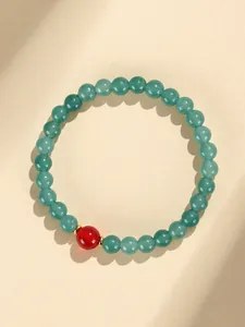 Nahaufnahme eines Perlenarmbands aus blauem Chalcedon mit einer markanten roten Achatperle.