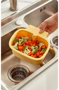 Close-up of a yellow kitchen sink drain basket with vegetables in a stainless steel sink