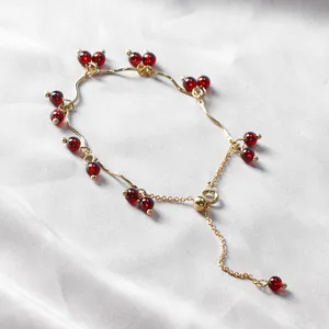 Elegante bracciale con perle di granato rosso vino e catena regolabile dorata su seta