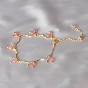 Elegante bracciale in quarzo fragola dorato da donna con design ondulato su fondo seta