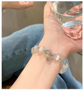 Detalle de una pulsera minimalista de cuentas de ojo de gato con colgante Fu de plata