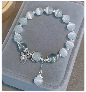 Primer plano de pulsera de piedra ojo de gato con dije de mariposa brillante
