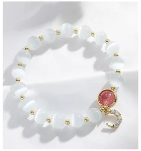 Detalle macro de elegante pulsera de cuentas de ojo de gato blanco con colgante de luna