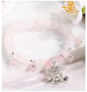 Primer plano de una pulsera de cuentas de ojo de gato rosa con candado ruyi de plata y cascabeles.