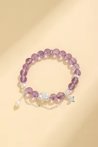 Dettaglio del bracciale di perle viola con ciondoli a loto, farfalla e perla