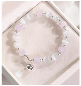 Primer plano de pulsera de cuentas de ojo de gato y cristal con colgante de cascabel de plata