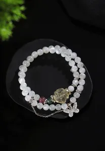 Vista detallada de una pulsera de piedra de luna con colgante de mariposa de plata